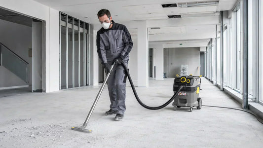 Trabajador usando aspiradora industrial Kärcher NT 30/1 Tact Te H para extraer polvo fino de cemento y sílice en una obra.